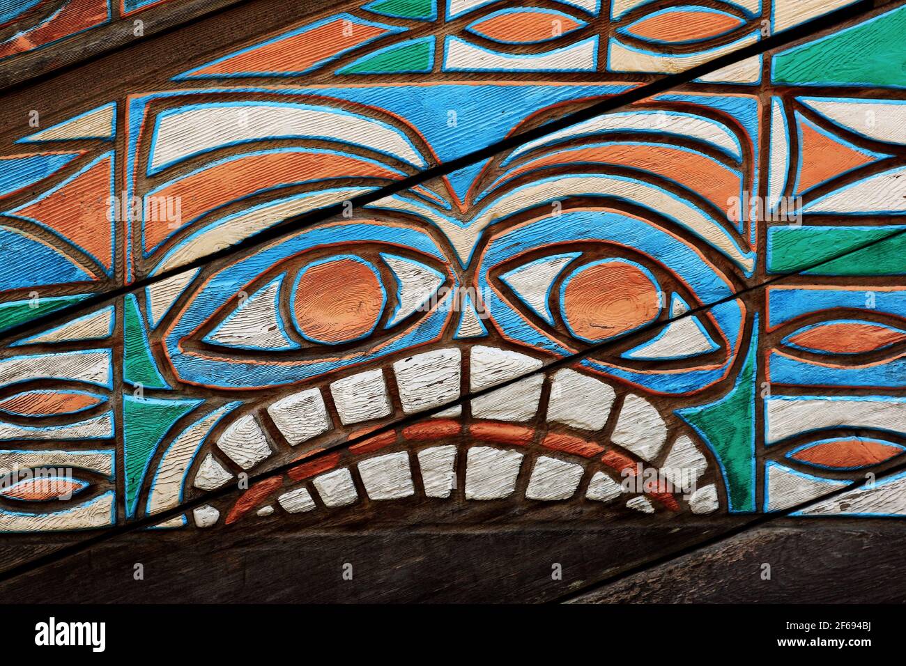 A tribal face etched and painted in wood. Stock Photo