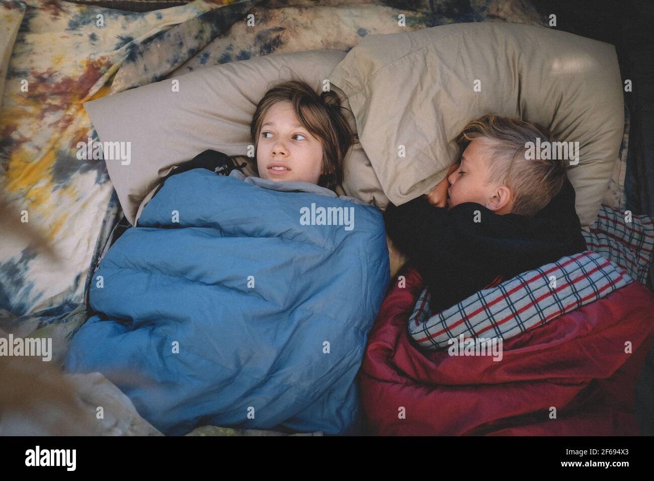 Two Friends Side by Side in Sleeping Bags. One looks scared. Stock Photo