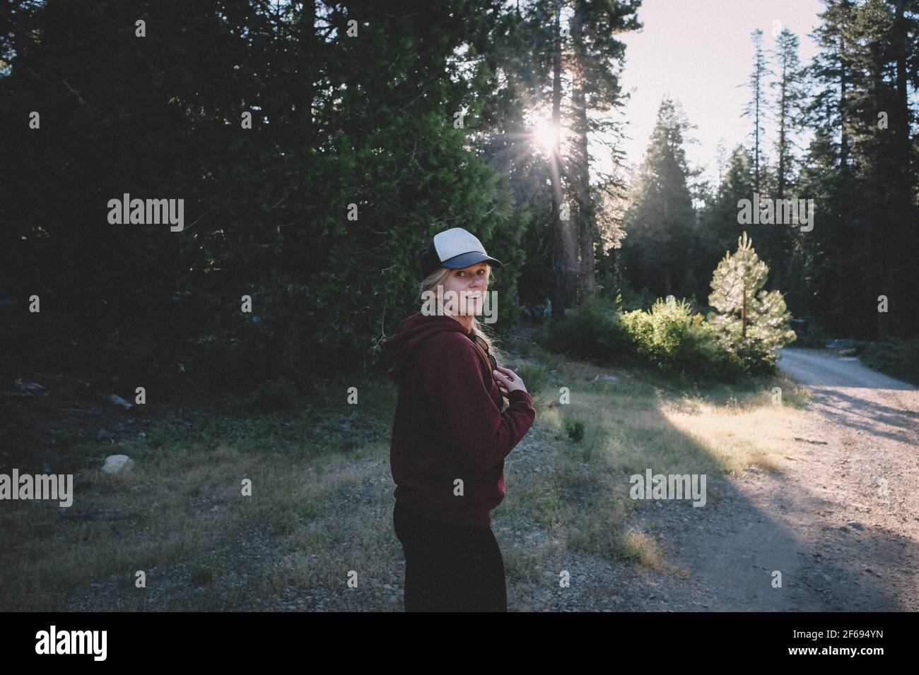 Pretty Blonde Girl begins morning hike on a dirt road in the Sierras Stock Photo