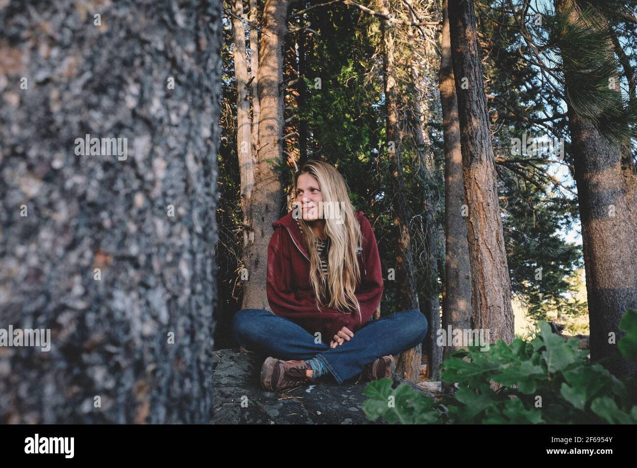 Blonde Woman sits peaceful in the Middle of a forest Stock Photo