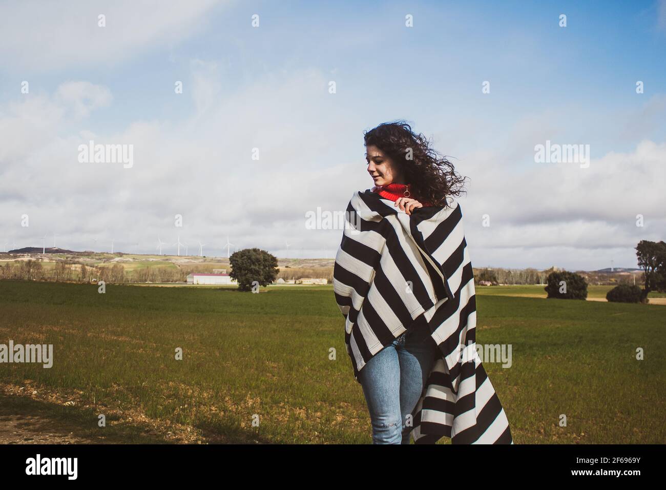 young woman in the field with striped blanket moving in the wind Stock Photo
