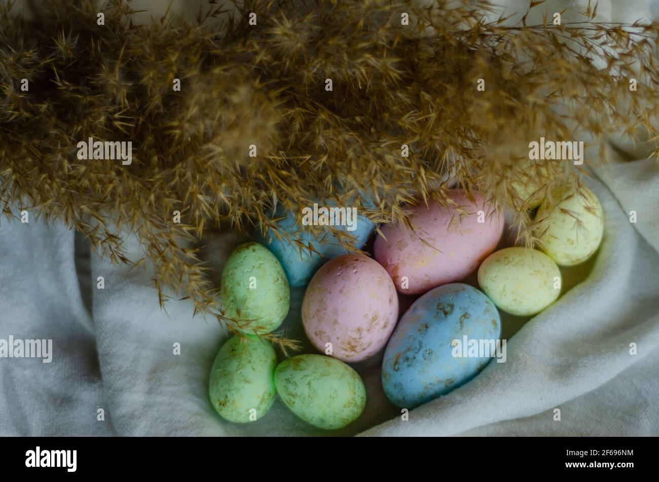 colorful Easter eggs on a light tablecloth with reeds Stock Photo