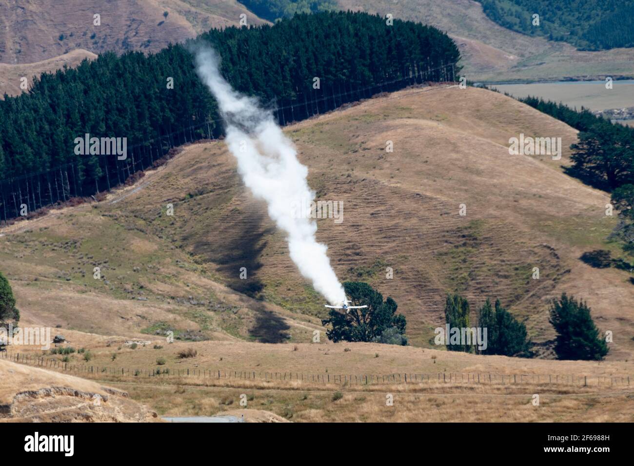 Aerial top dressing of fertilizer on hill country farmland at Otahome, near Castlepoint, Wairarapa, North Island, New Zealand Stock Photo