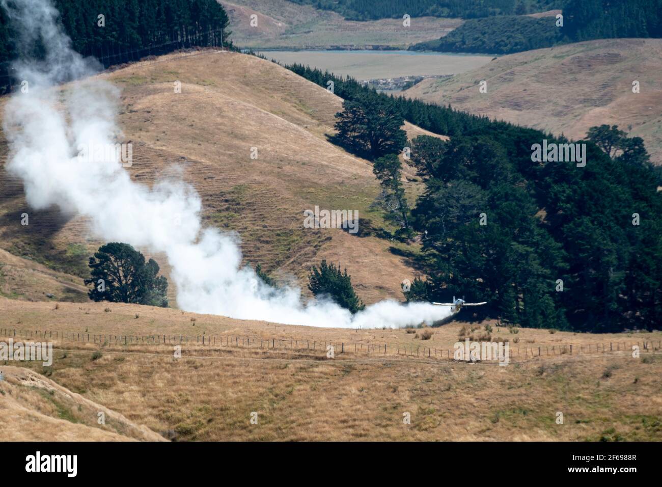 Aerial top dressing of fertilizer on hill country farmland at Otahome, near Castlepoint, Wairarapa, North Island, New Zealand Stock Photo
