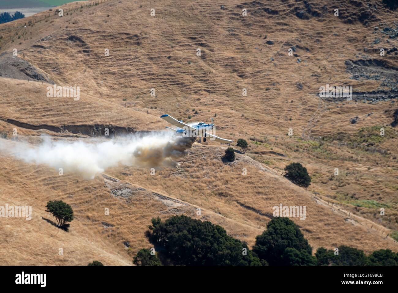Aerial top dressing of fertilizer on hill country farmland at Otahome, near Castlepoint, Wairarapa, North Island, New Zealand Stock Photo