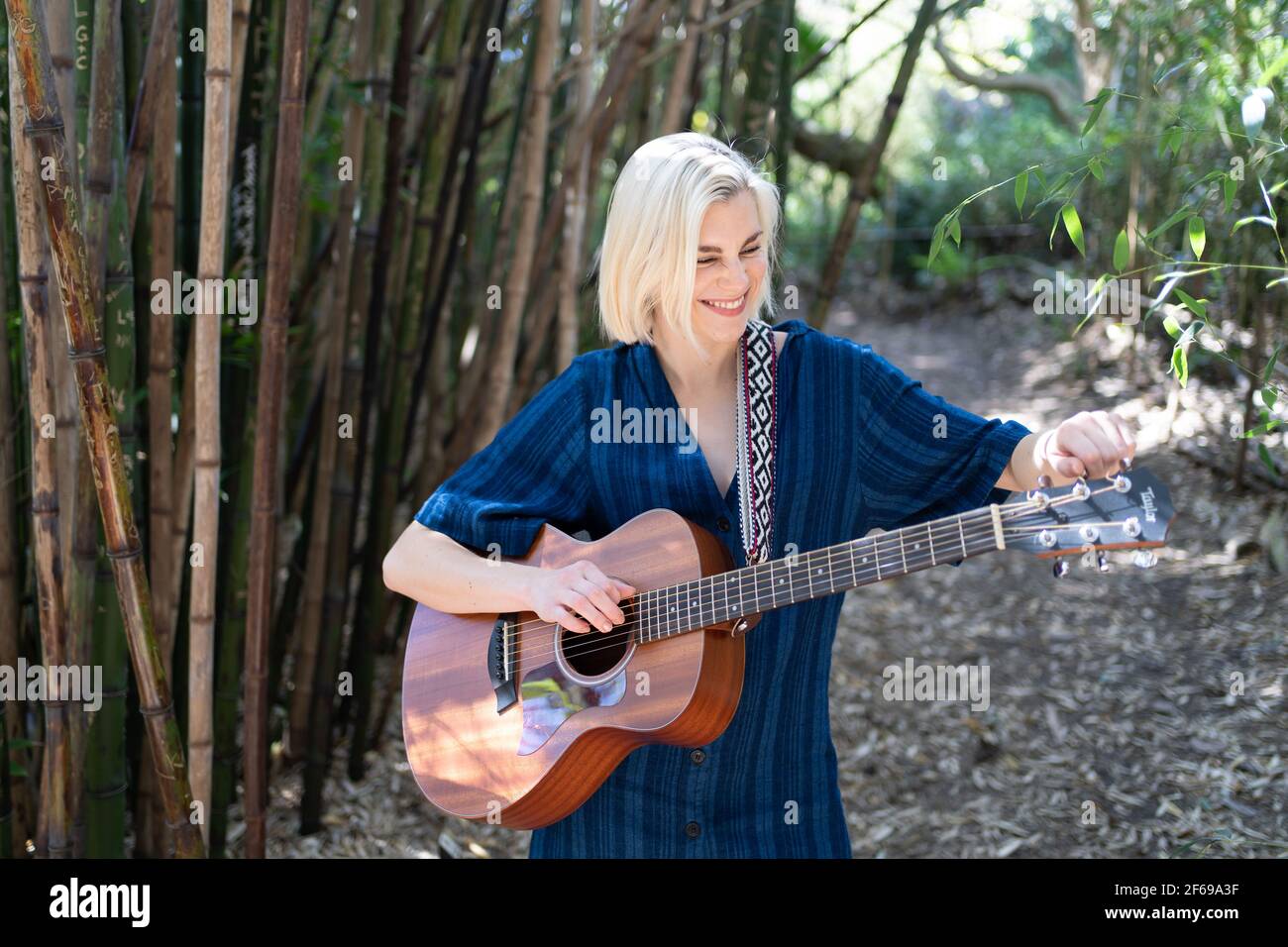 young woman playing guitar and singing in bamboo forest garden Stock Photo