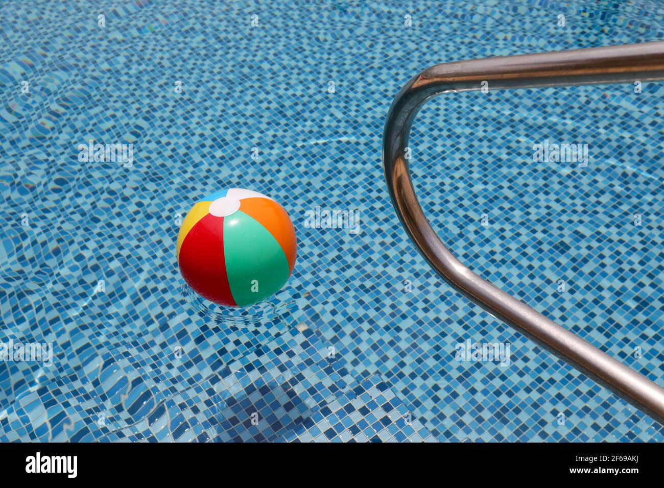 Beach ball in pool. Colorful inflatable ball floating in swimming pool, summer vacation concept. Stock Photo