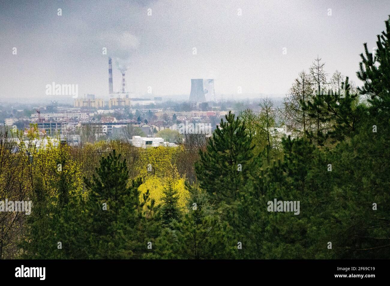 Industrial part of city of Krakow, Poland with power plants and factory chimneys, fir trees, Environmental concept, pollution Stock Photo
