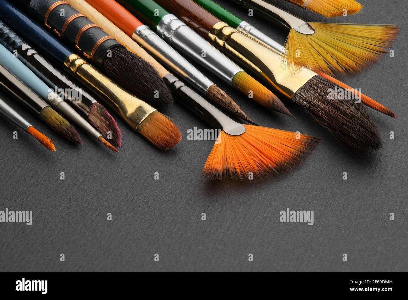 Artistic paintbrush for watercolor painting closeup. Different shape and size paint brushes on black paper background. Set of brushes for painting. Stock Photo