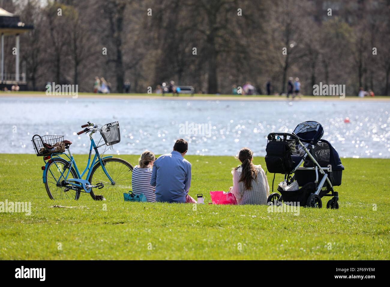 a-group-of-people-sit-by-a-lake-while-enjoying-the-sunshine-on-the