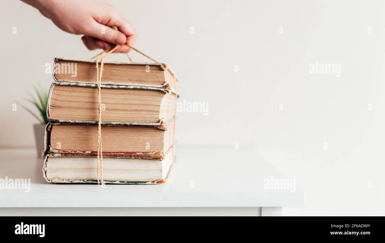 Hand holding a stack of old books in the library, concept of learning, study and education, concept of science, wisdom and knowledge. High quality pho Stock Photo