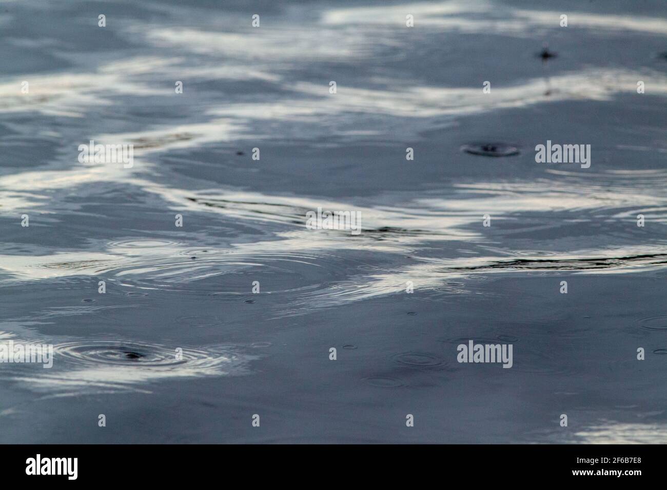 Swell Patterns, shapes, created, formed, forming, evolving, from continuous, continuing, falling raindrops on a flowing river surface. Highlight, high Stock Photo