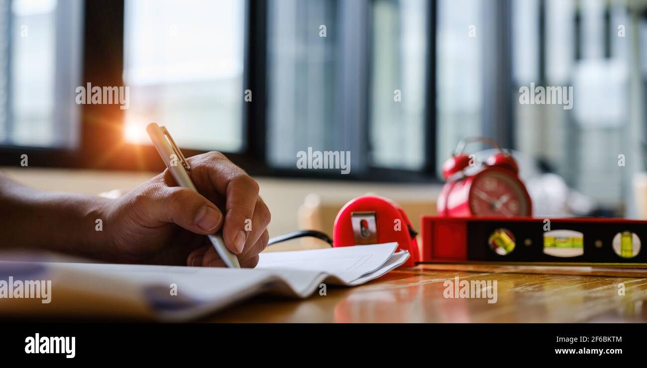 Business engineer hand holding pen with construction drawing. consulting planning for engineering concept. Stock Photo