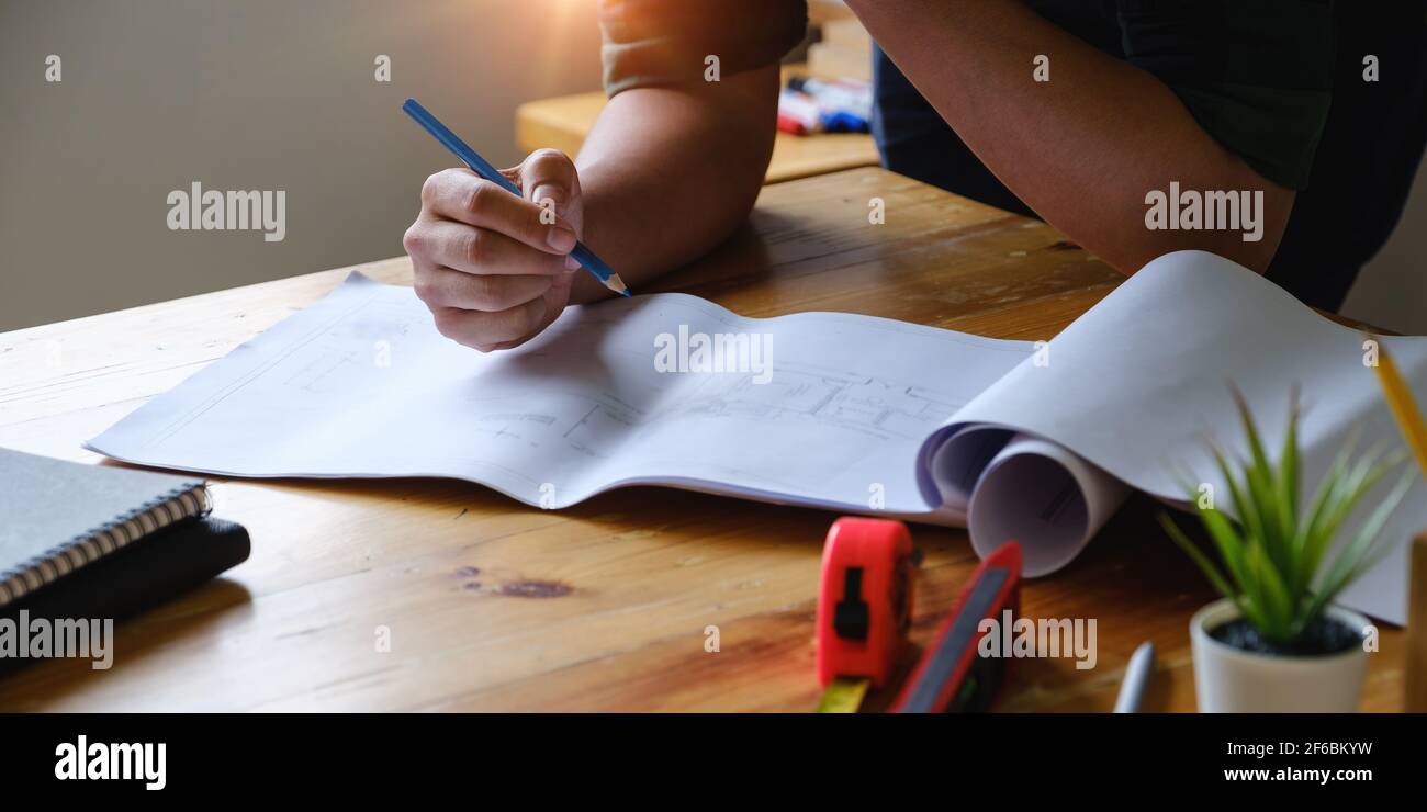 Business engineer hand holding pencil with construction drawing. consulting planning for engineering concept. Stock Photo