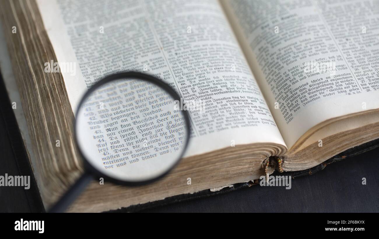 Opening ancient bible, text reading through magnifying glass. Search for  truth and meaning of life. Religious book. Russia, 27.12.2020 Stock Photo -  Alamy