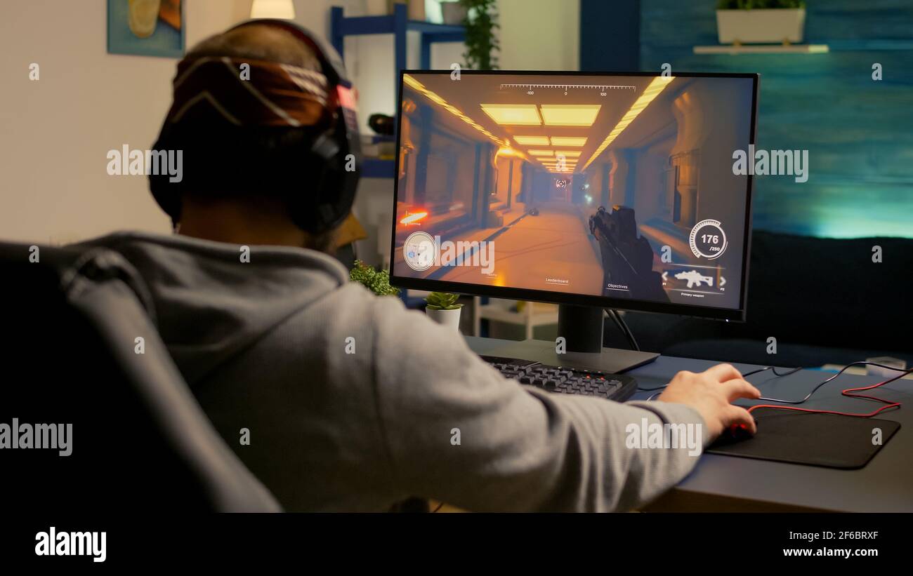Back of pro gamer playing first person shooter video game on professional  computer for cyber esport competition. Pro player talking with multiple  players using headset during online tournament Stock Photo - Alamy