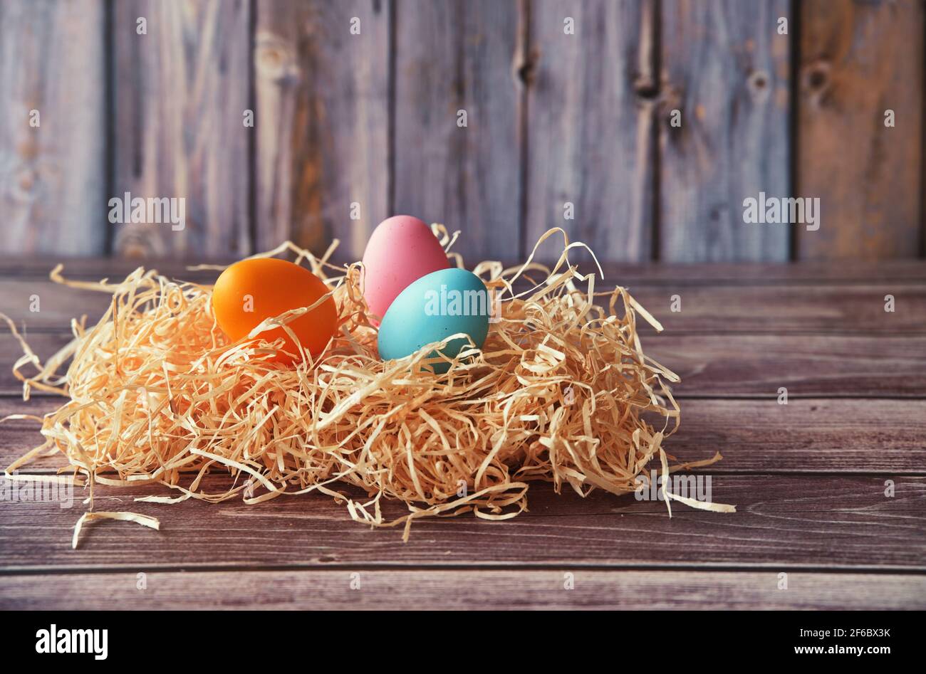 Easter eggs in straw on wooden background Stock Photo