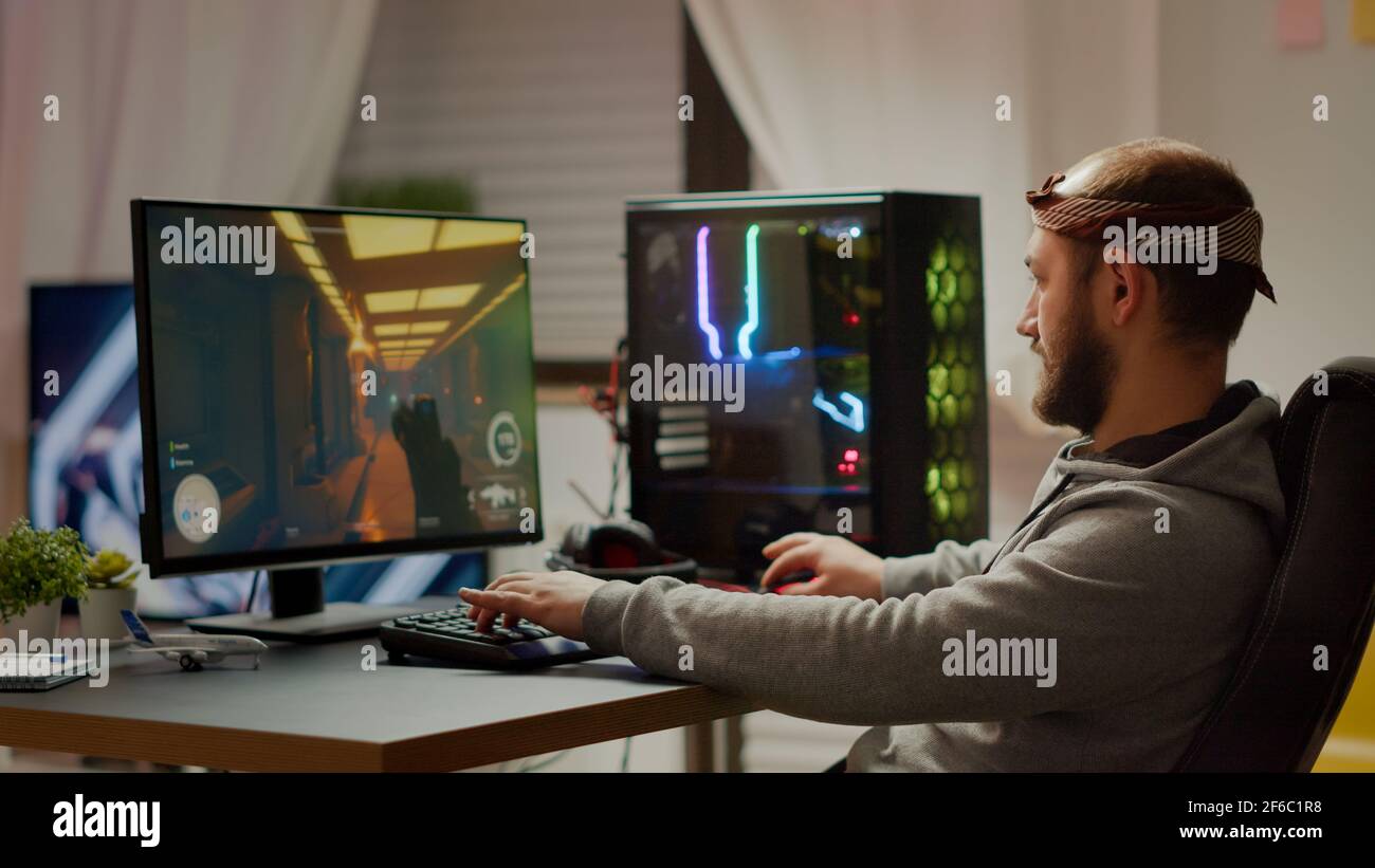 Back shot of pro gamer playing online shooter game on computer using  wireless controller. Competitive player man winning videogame tournament  use professional equipment at home gamming studio Stock Photo - Alamy