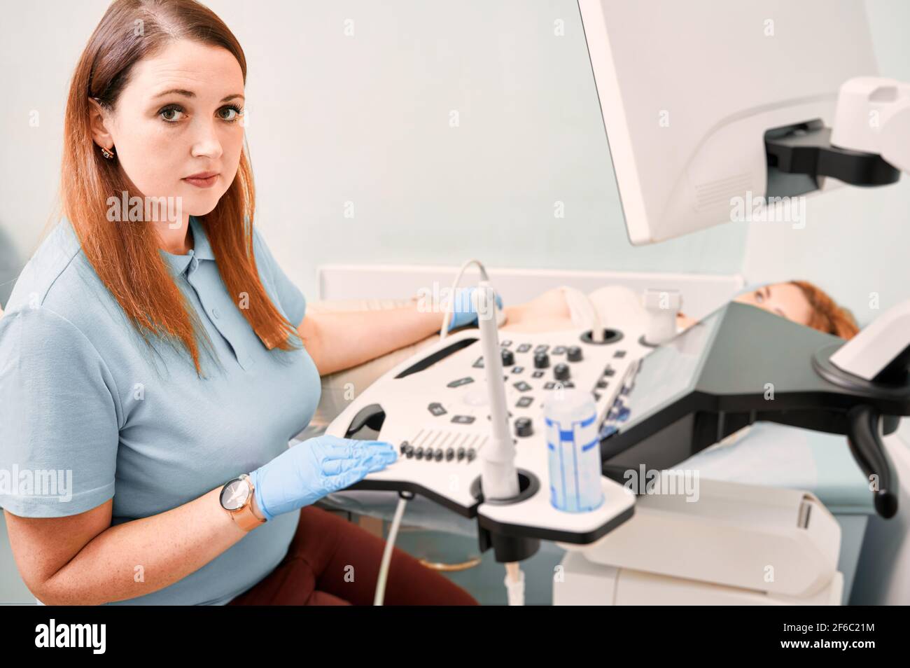 Nice female doctor performing ultrasound procedure in clinic. Stock Photo