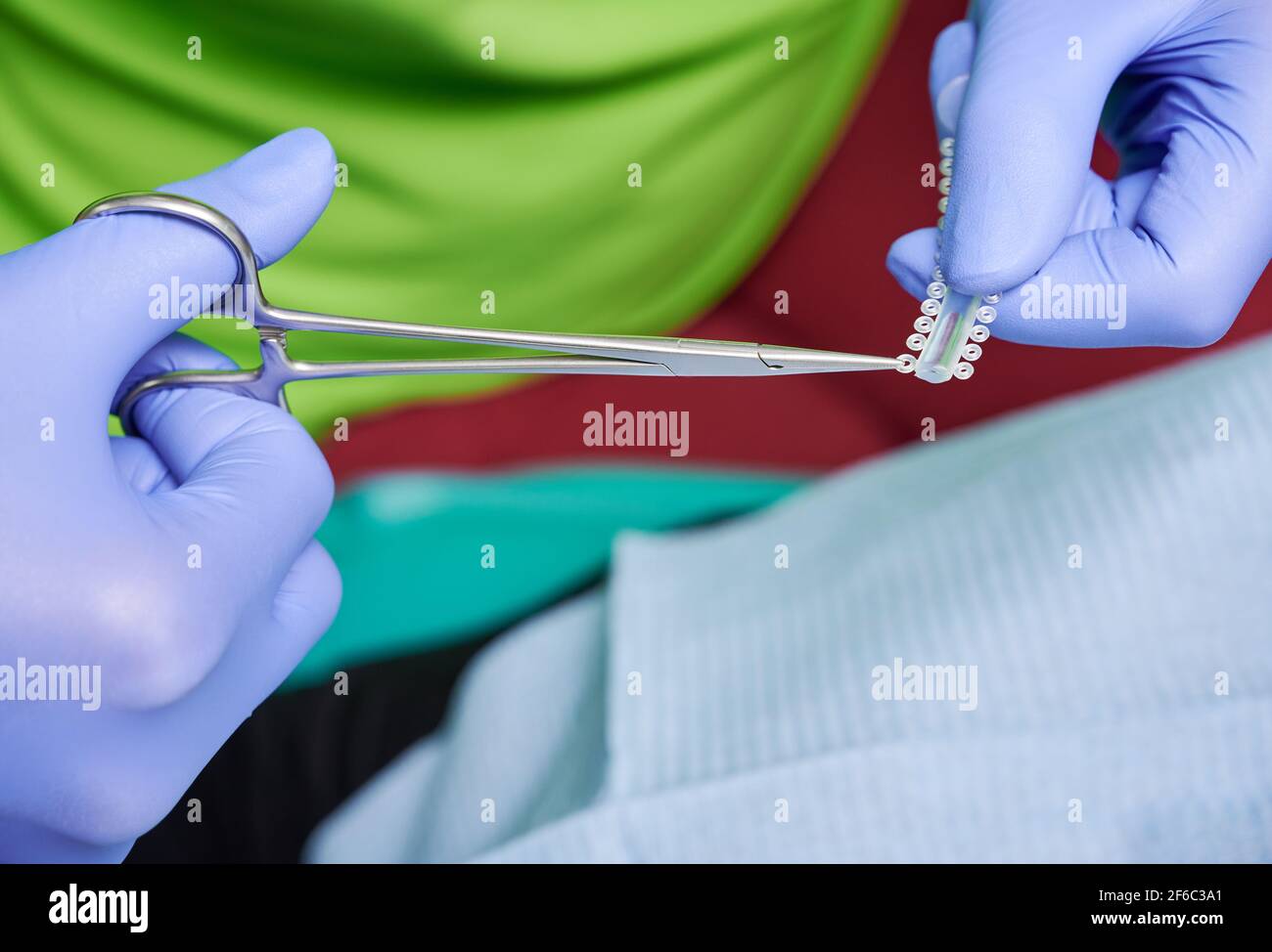 Orthodontist hands cutting elastic ligature ties with dental scissors. Stock Photo