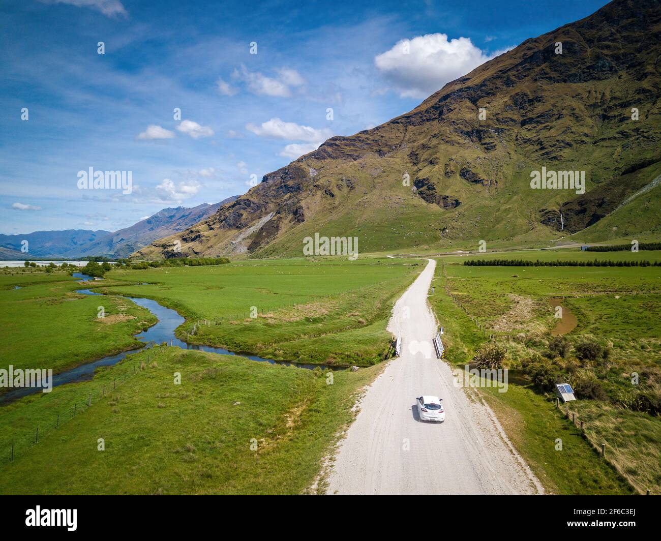 White car driving on dirt road. Wild nature. Aerial view of New Zealand fantastic landscapes and scenery. Stock Photo