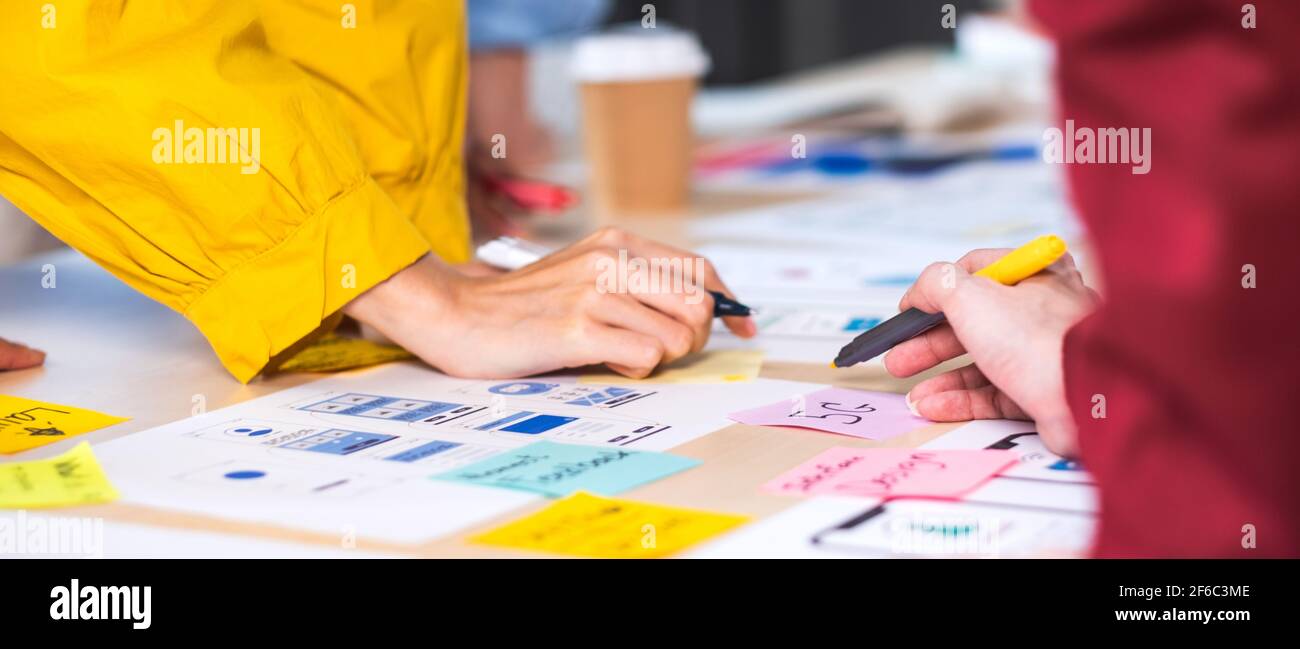 Close up hand ux developer and ui designer brainstorming about mobile app interface wireframe design on table at modern office.Creative digital develo Stock Photo
