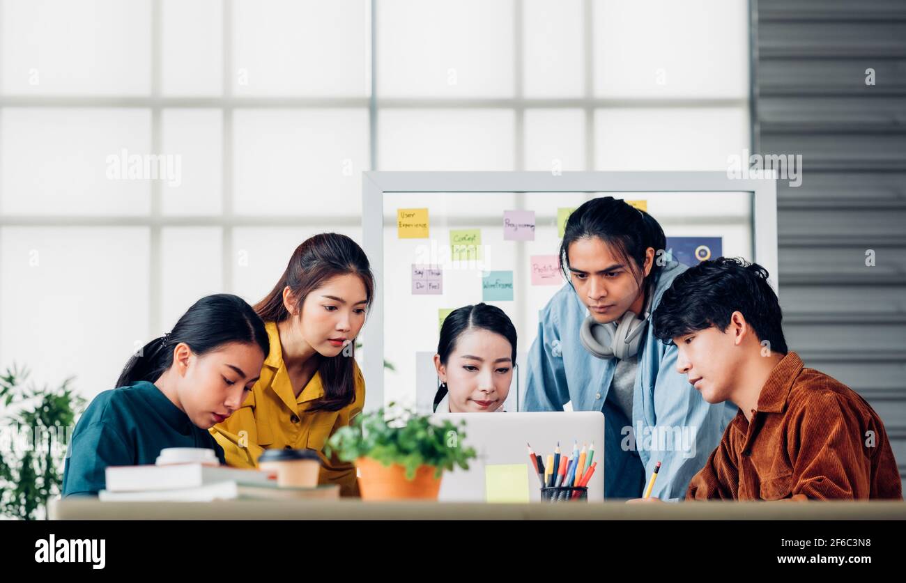 group of asian ux developer and ui designer serious brainstorming about mobile app interface on meeting table at modern office.Creative digital develo Stock Photo