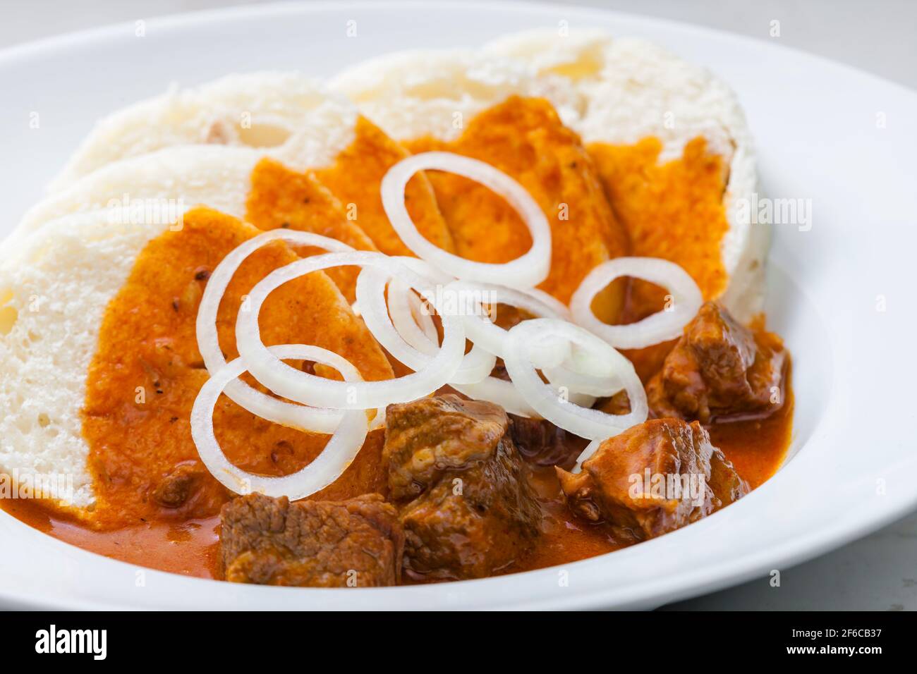 beef goulash with dumplings and rings of white onion Stock Photo