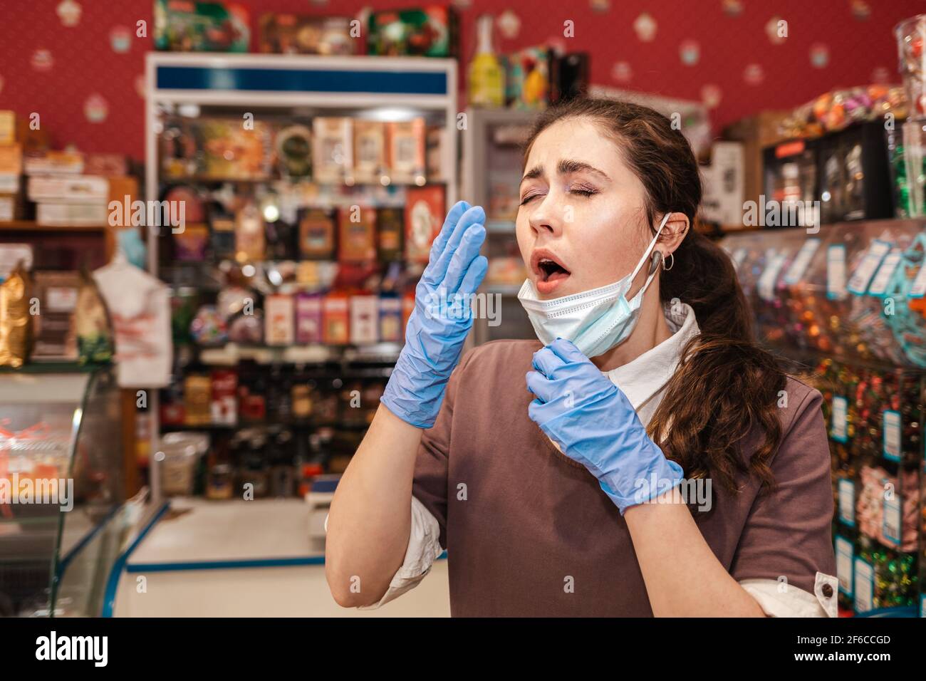 Virus. A woman in rubber gloves puts down her mask to sneeze. Grocery ...