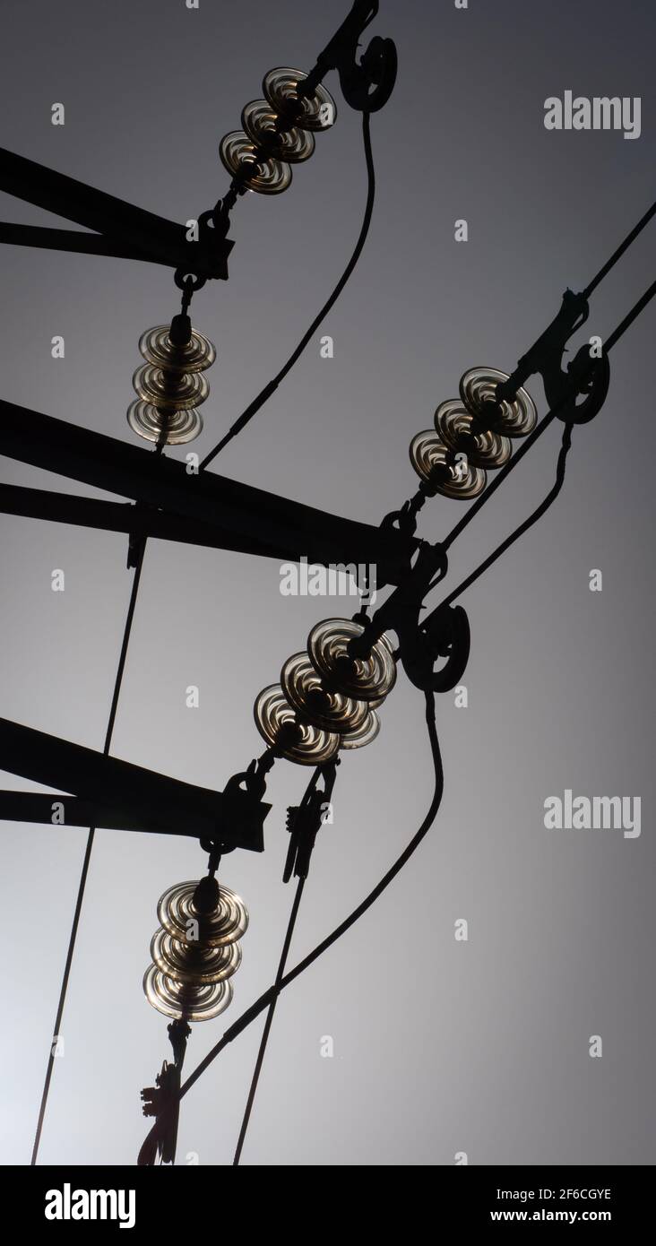 Cables and insulators silhouetted against a clear sky attached to an electricity pole in Westbury, Wiltshire, England, UK. Stock Photo