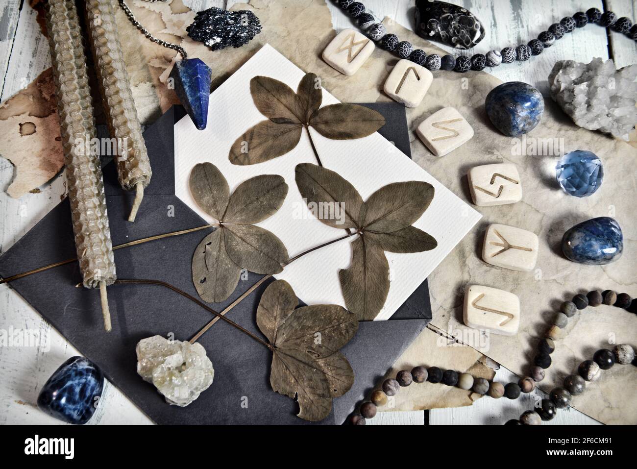 Grunge still life with four leaf clover, runes, candles and crystals on ...
