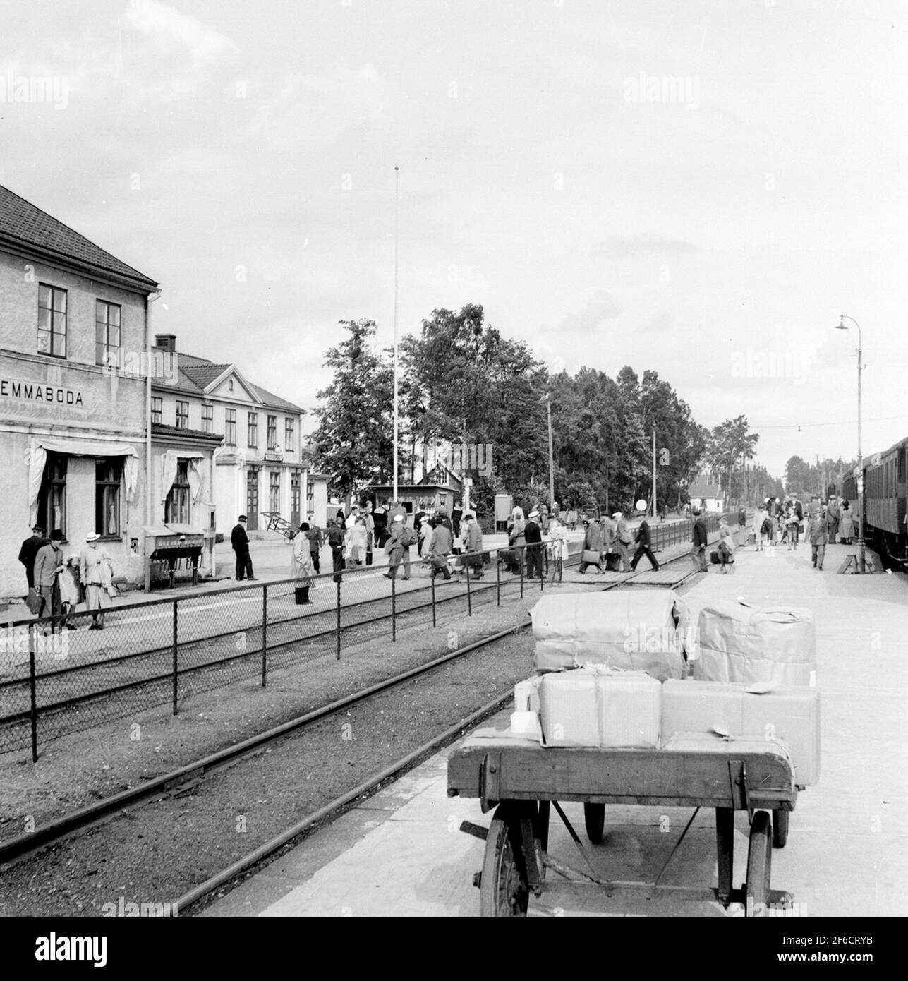Emmaboda railway station. The passenger train consists of older cars manufactured before 1930. The telephone booth in the picture is of 1930s model, and the existence of military people among the travelers makes it likely that the picture is taken sometime during the war years. Stock Photo