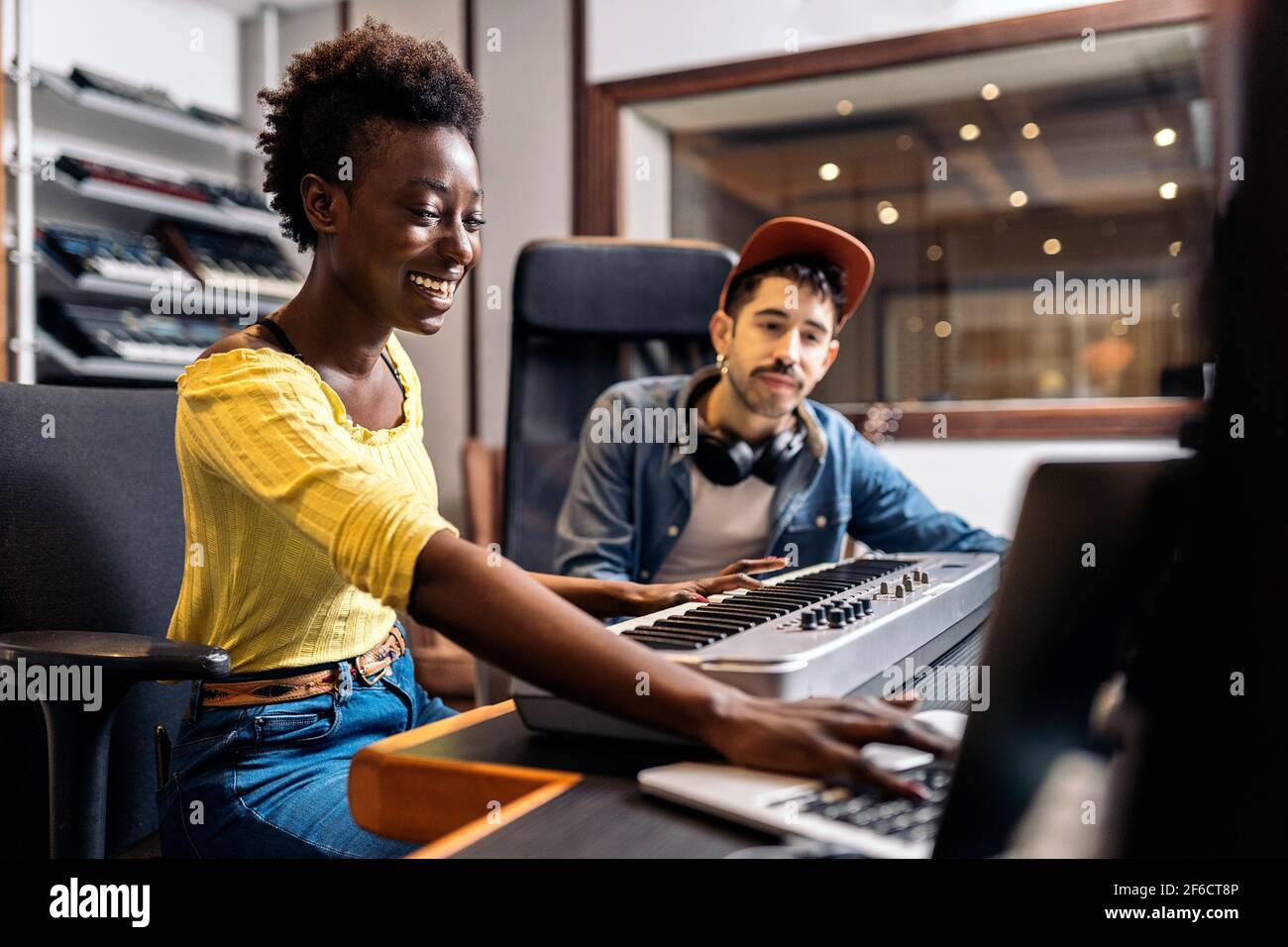 Stock photo of black woman playing electronic piano keyboard in music studio. Stock Photo