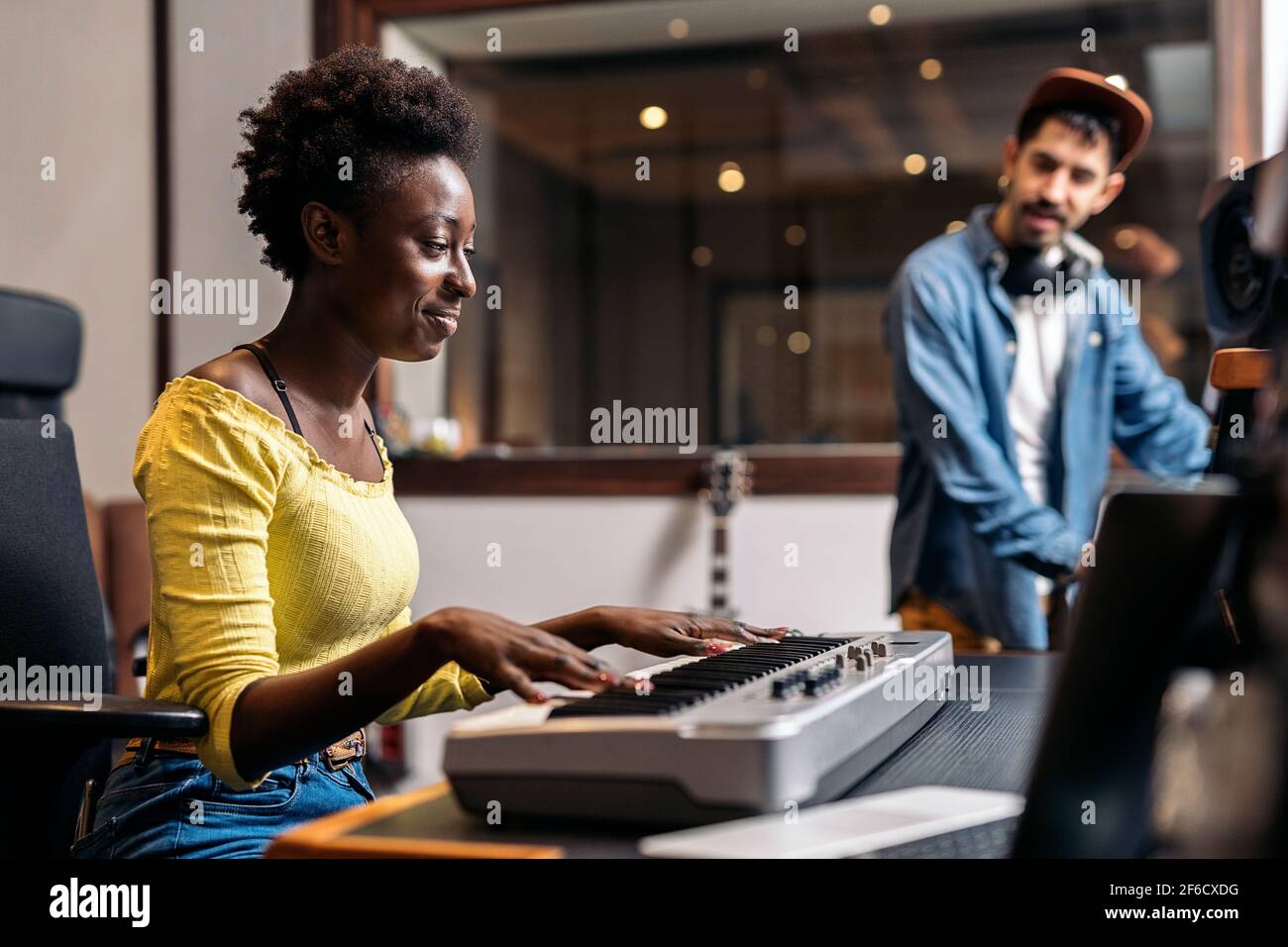 Stock photo of black woman playing electronic piano keyboard in music studio. Stock Photo