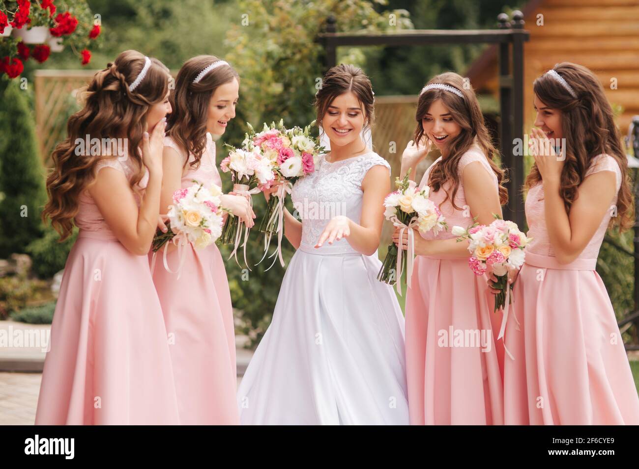 Happy bride with bridesmaid hold bouquets and have fun outside. Beautiful  bridesmaid in same dresses stand by the charming bride in long wedding dress  Stock Photo - Alamy