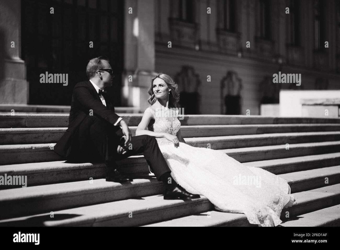 Fashion photo of wedding couple. Groom wears blue suit and tie bow. Bride  wears white wedding dress. Black and white Stock Photo - Alamy