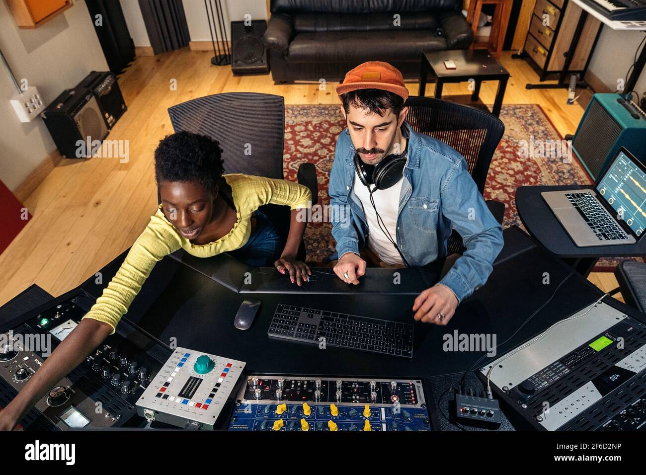 Stock photo of male music producer working with black singer in cool music studio. Stock Photo