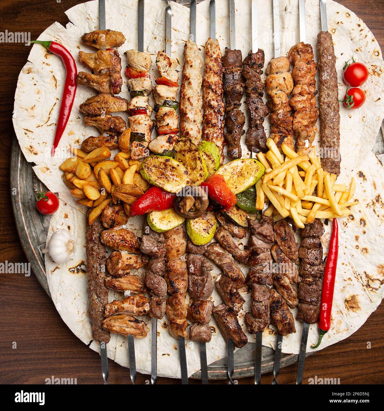 Assorted delicious grilled meat on skewers with vegetables and French fries on pita. Top view Stock Photo