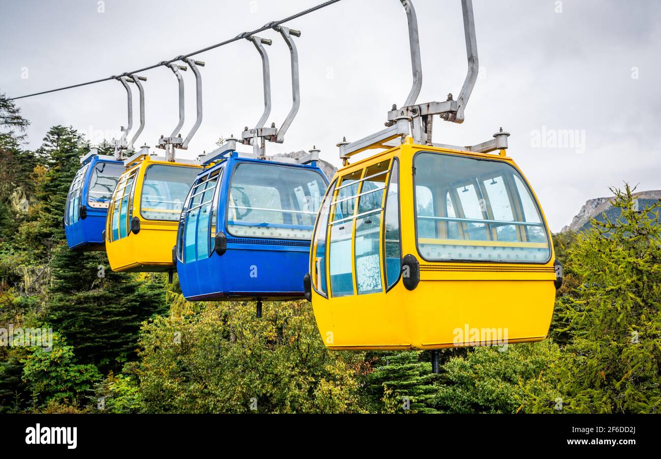 View of ropeway with four blue and yellow fixed grip cable car Stock Photo
