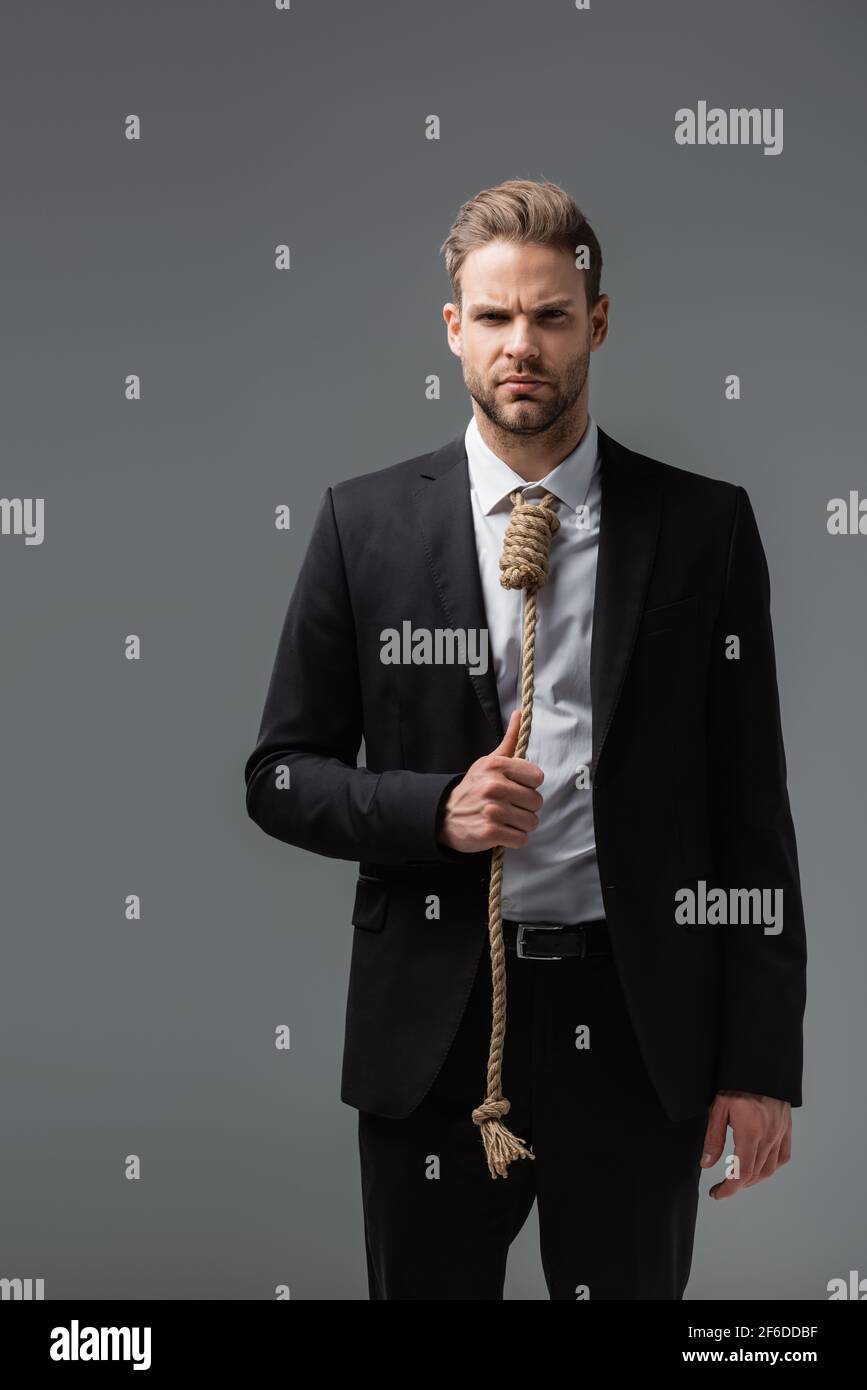 tense businessman in black suit, with rope instead of tie, looking at  camera isolated on grey Stock Photo - Alamy