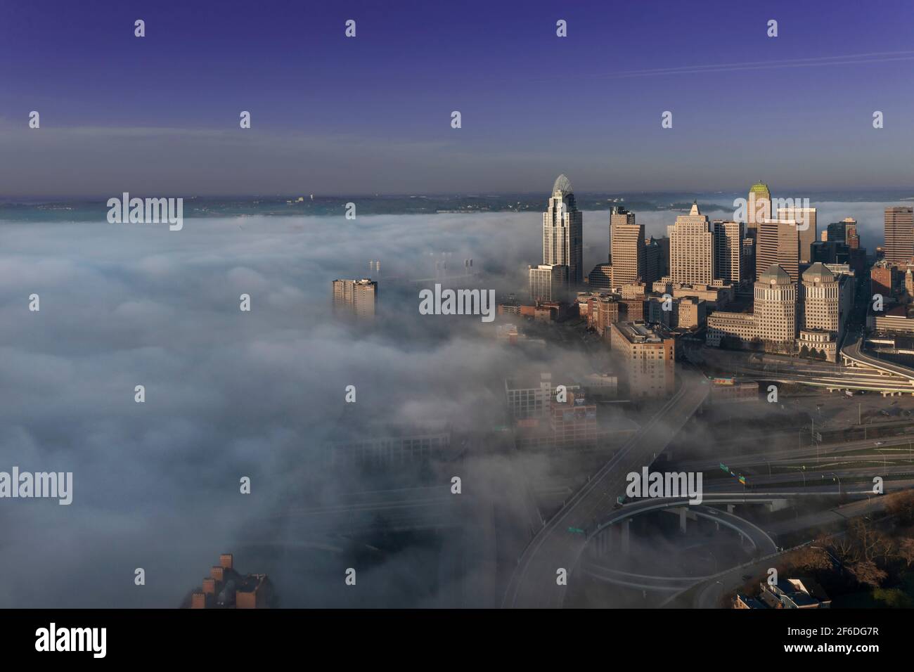 Early morning fog blankets the Ohio River over downtown Cincinnati and Kentucky as the sun illuminates buildings and bridges through the clouds of fog Stock Photo