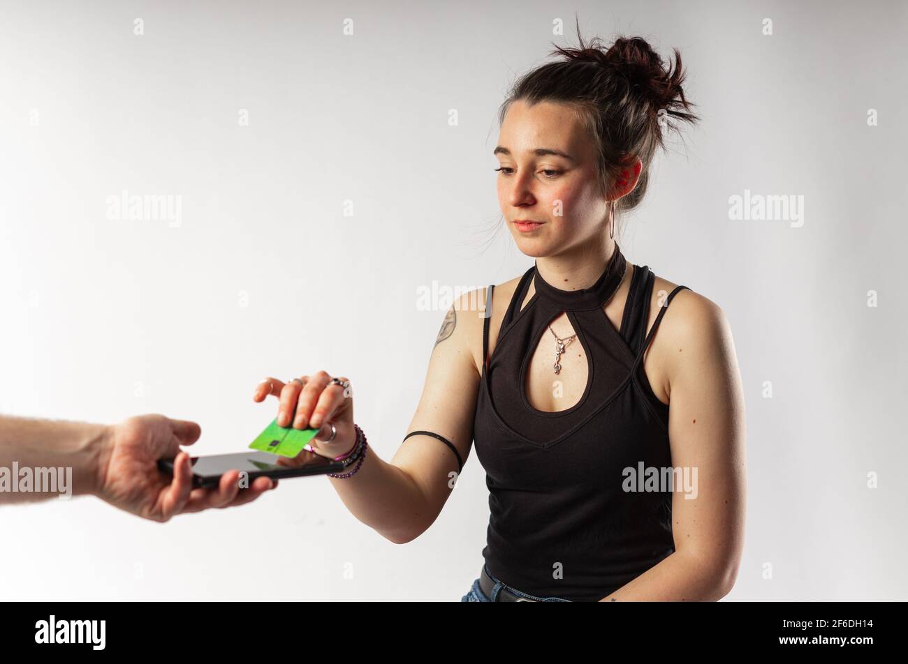 Alternative young woman with tattoos paying with her contactless credit