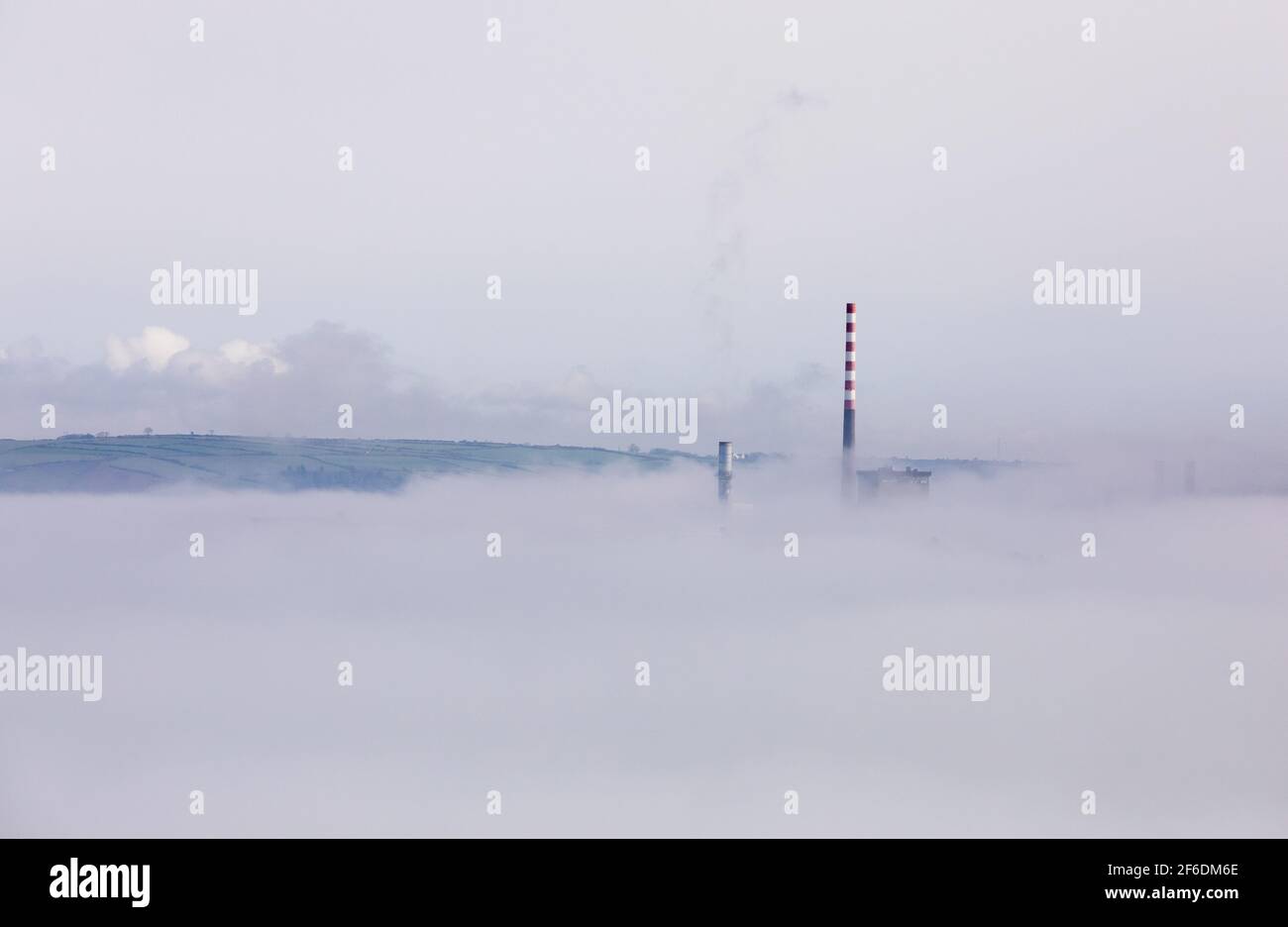 Aghada,  Cork, Ireland. 31st March, 2021.Early morning sun begins to disapate the sea fog that shrouds the storage tanks at the oil refinery and the electric generating station in Aghada, Co. Cork, Ireland. - Credit; David Creedon / Alamy Live News Stock Photo