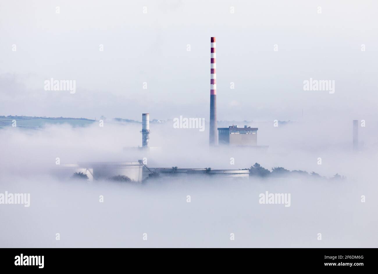 Aghada,  Cork, Ireland. 31st March, 2021.Early morning sun begins to disapate the sea fog that shrouds the storage tanks at the oil refinery and the electric generating station in Aghada, Co. Cork, Ireland. - Credit; David Creedon / Alamy Live News Stock Photo