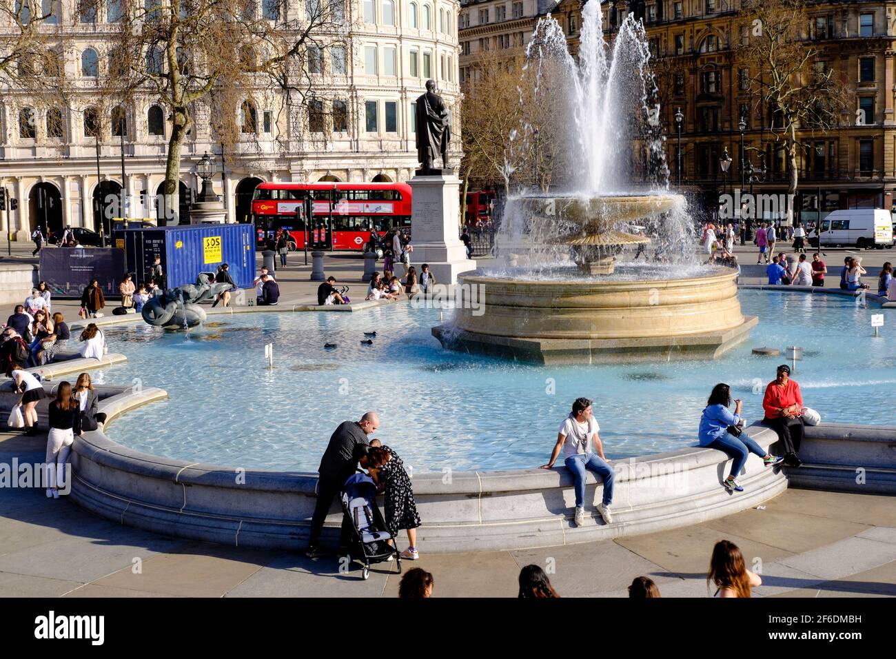 People enjoying the Spring sunshine in London's Trafalgar Square following the UK Government's easing of Covid restrictions permitting groups of up to six people or two households in England to meet outside. Stock Photo