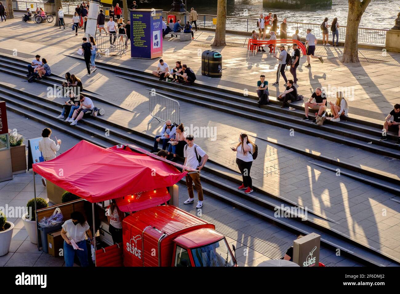 People enjoying the Spring sunshine on London's South Bank following the UK Government's easing of Covid restrictions permitting groups of up to six people or two households in England to meet outside. Stock Photo