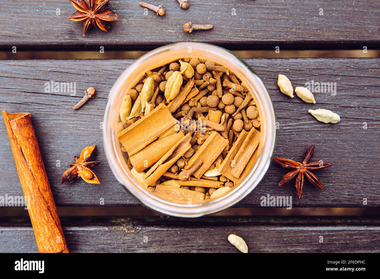 Various homemade chai tea ground ingredients in glass jar, flat lay view. Green cardamom pods, cinnamon sticks, cloves, star anise. Above view. Stock Photo