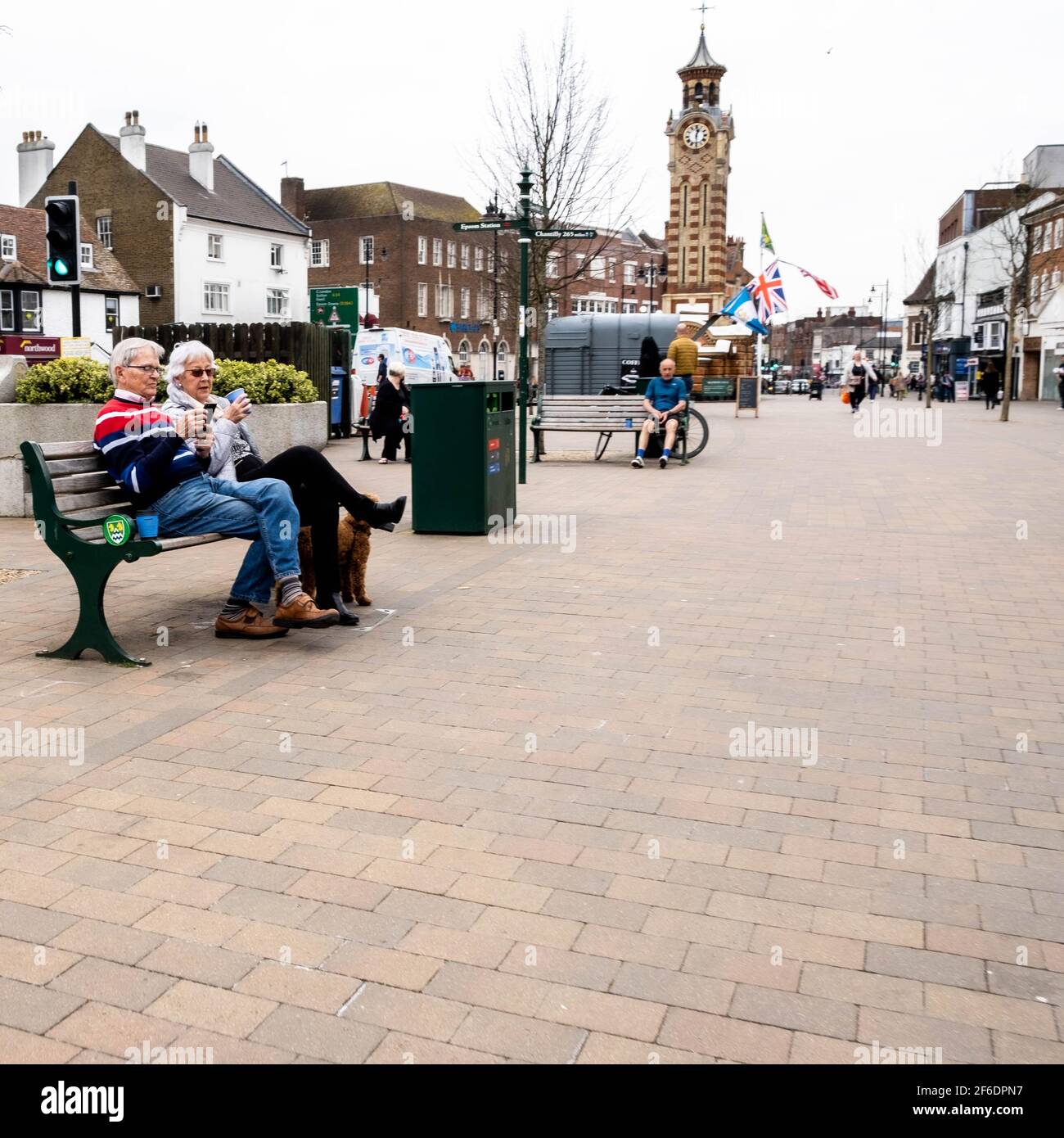 Epsom Surrey London UK, March 31 2021, Senior Man Woman Couple Sitting On An Outdoor Seat Or Bench Relaxing With Coffee Stock Photo