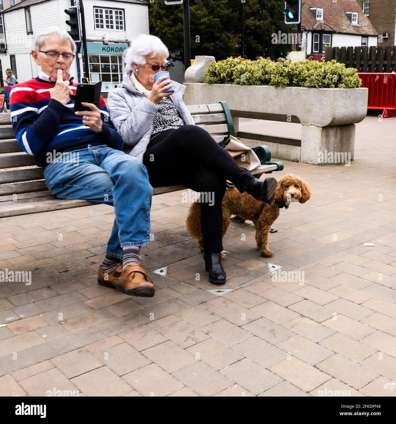 Epsom Surrey London UK, March 31 2021, Senior Man Woman Couple Sitting On An Outdoor Seat Or Bench Relaxing With Coffee Stock Photo