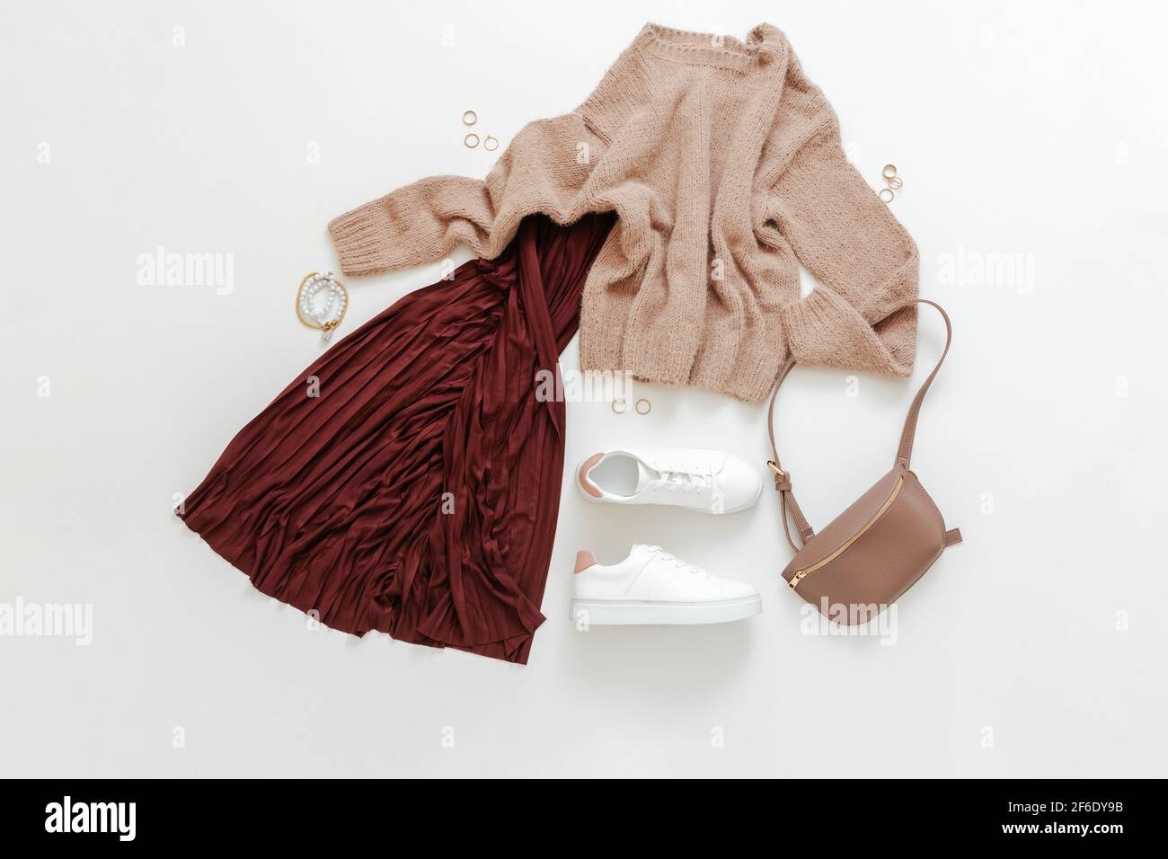 Female spring look autumn outfit burgundy skirt beige sweater white shoes  sneakers bag. Folded fly clothes for women fashion urban basic outfit with  a Stock Photo - Alamy